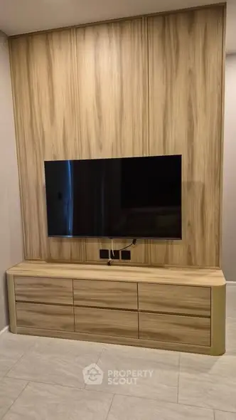 Modern living room with sleek wooden TV unit and mounted flat-screen television.