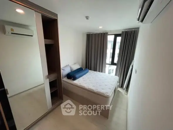 Modern bedroom with mirrored wardrobe and large window in a stylish apartment.