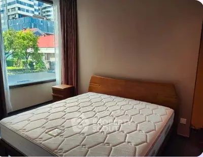 Spacious bedroom with large window offering city view and natural light