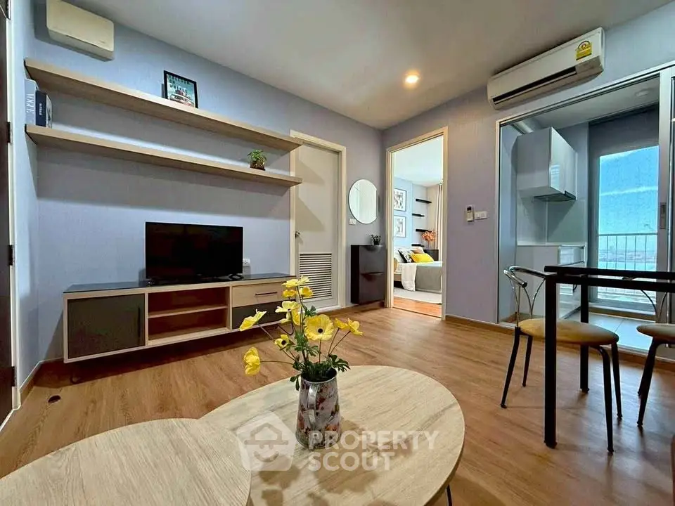 Modern living room with wooden flooring, stylish furniture, and open kitchen layout in a cozy apartment.