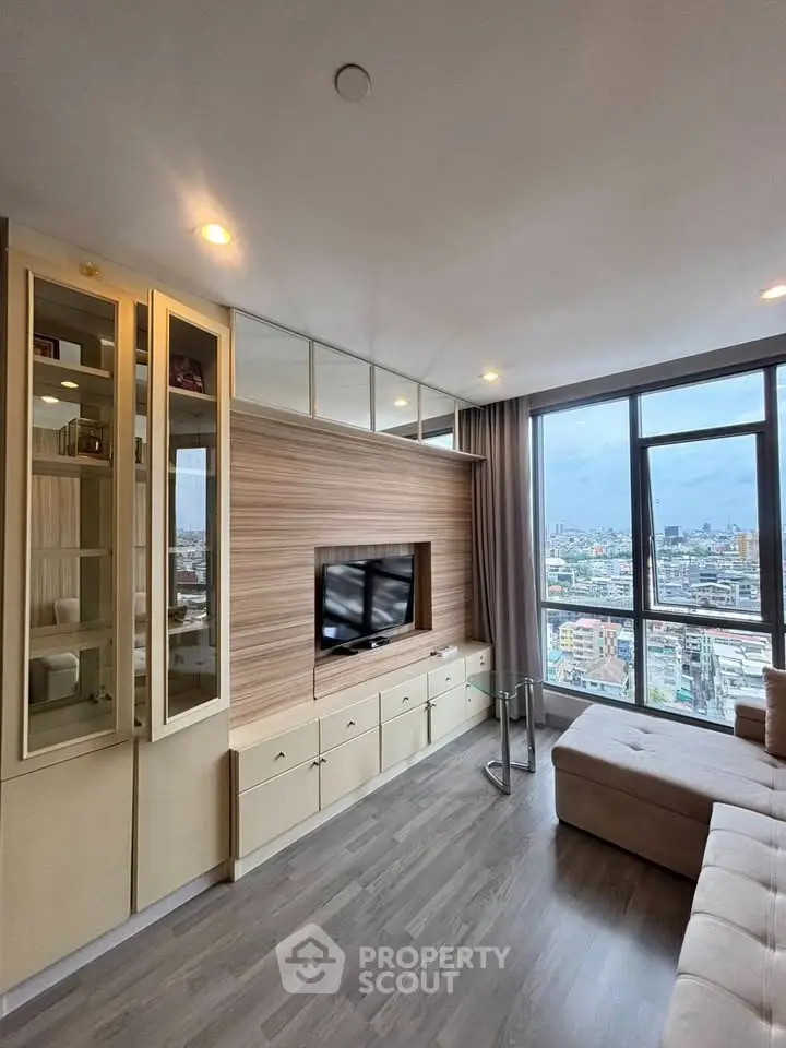 Modern living room with city view, featuring sleek cabinetry and large windows for natural light.