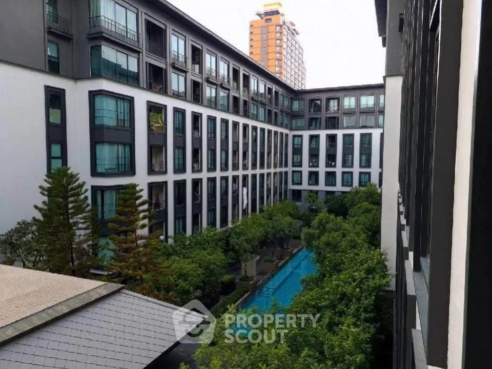 Modern apartment complex with lush greenery and inviting swimming pool view.