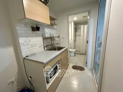 Compact kitchen with modern appliances and adjacent bathroom in cozy apartment