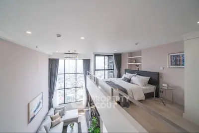 Luxurious loft apartment with modern bedroom and spacious living area, featuring large windows and elegant decor.