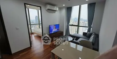 Modern living room with city view, featuring sleek furniture and large windows.