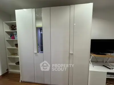 Spacious modern bedroom with sleek white wardrobe and entertainment unit