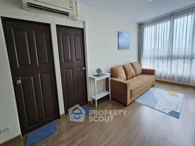 Modern living room with brown sofa, wooden floor, and large window with sheer curtains.