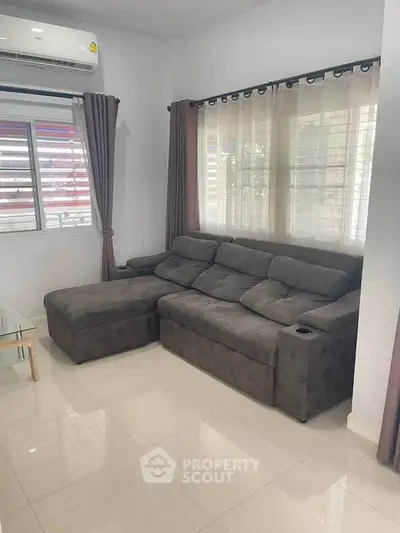 Cozy living room with modern gray sectional sofa and large window, perfect for relaxation.