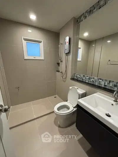 Modern bathroom with sleek fixtures and large mirror, featuring a walk-in shower and contemporary design.