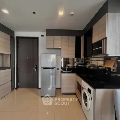 Modern kitchen with sleek cabinetry, stainless steel fridge, and built-in washing machine in a stylish apartment.