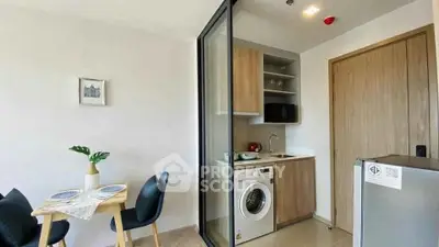 Modern compact kitchen with washing machine and dining area in stylish apartment.