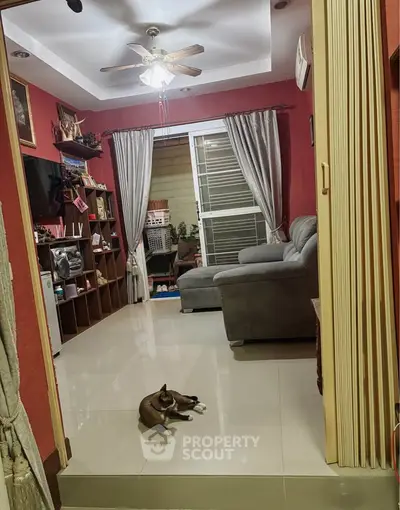 Cozy living room with modern decor and ceiling fan, featuring a comfortable sofa and stylish shelving.