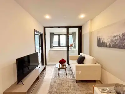 Modern living room with balcony view, featuring sleek furniture and natural light.