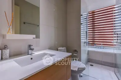 Modern bathroom with sleek fixtures and a glass-enclosed bathtub.