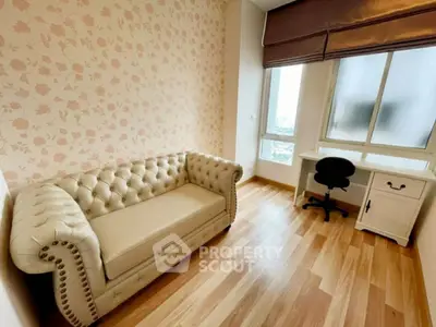 Charming study room with elegant sofa and desk, featuring floral wallpaper and large window view.