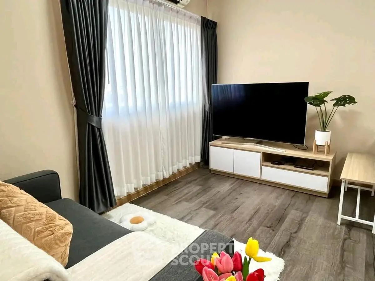 Cozy living room with modern decor and large window, perfect for relaxation.