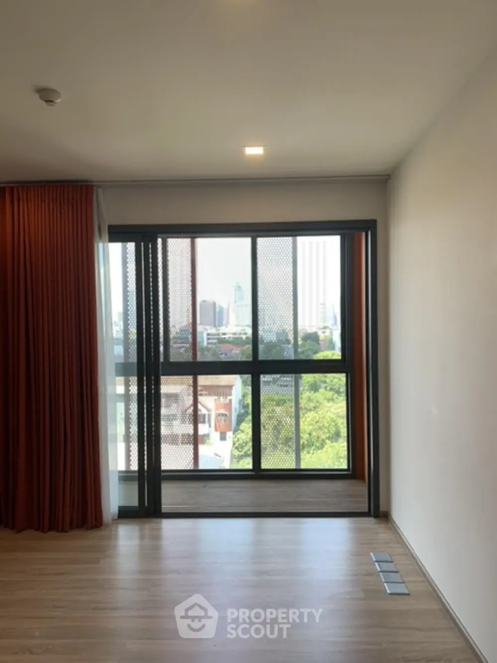 Spacious room with large window offering a stunning city view, perfect for modern living.