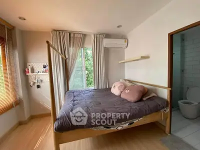Cozy bedroom with large window, wooden flooring, and modern decor.
