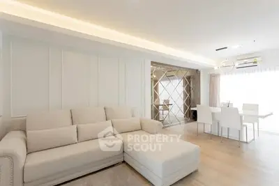 Elegant modern living room with plush sofa and dining area, featuring chic decor and ample natural light.