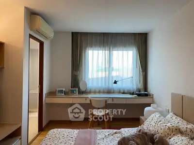 Cozy bedroom with stylish decor and natural light, featuring a work desk and air conditioning.