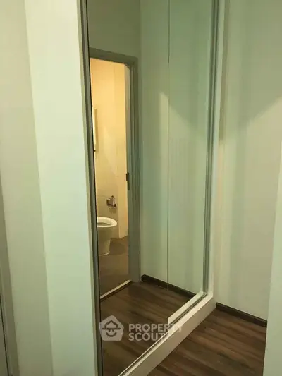Modern apartment hallway with mirrored closet and view into bathroom