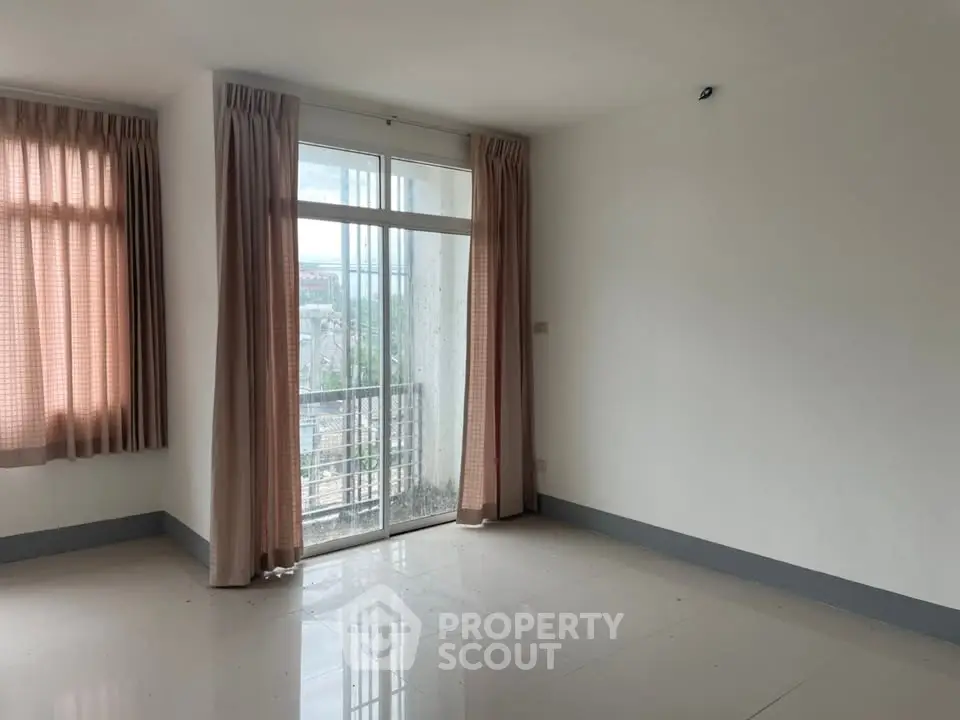 Spacious empty room with large windows and balcony access, perfect for customization.