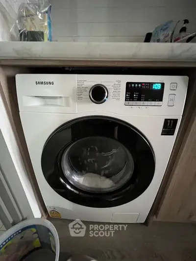 Modern Samsung washing machine in a stylish laundry setup with wooden cabinetry.