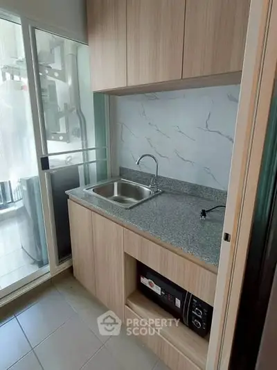 Modern compact kitchen with sleek cabinetry and granite countertop in urban apartment