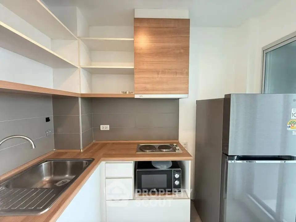Modern kitchen with sleek appliances and wooden countertops in a compact layout.