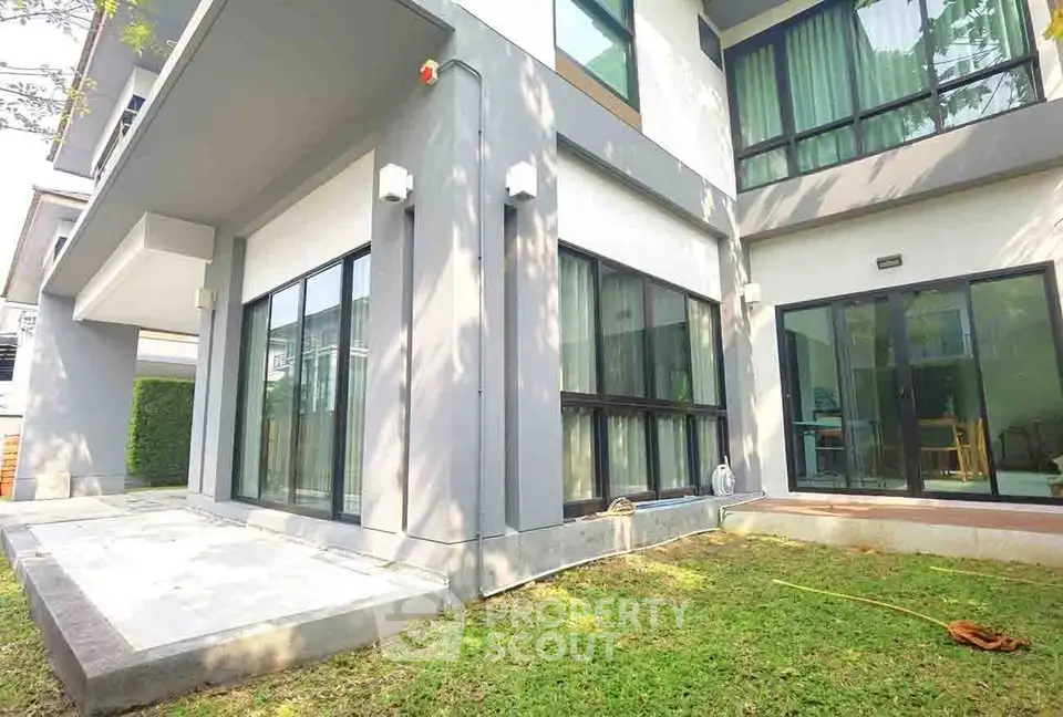 Modern two-story house with large windows and lush green lawn