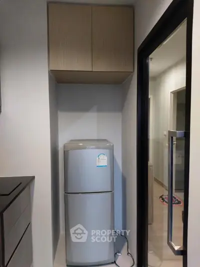 Compact kitchen area with modern fridge and overhead cabinets