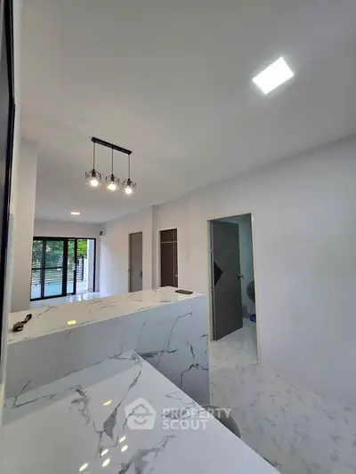 Modern open-layout kitchen with marble countertops and stylish lighting