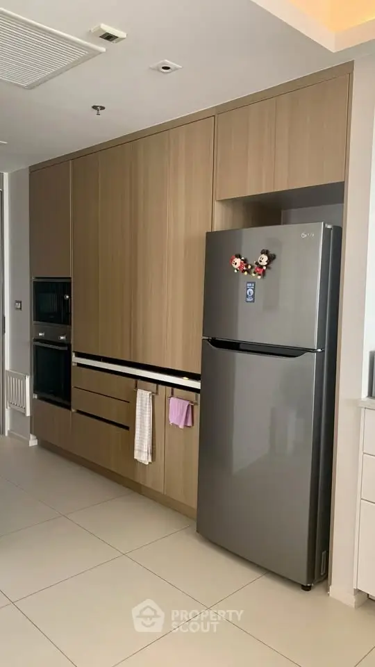 Modern kitchen with sleek cabinetry and stainless steel fridge, featuring built-in oven and minimalist design.