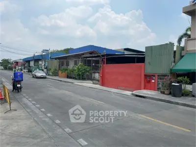 Industrial property with red gate and blue roof on a quiet street