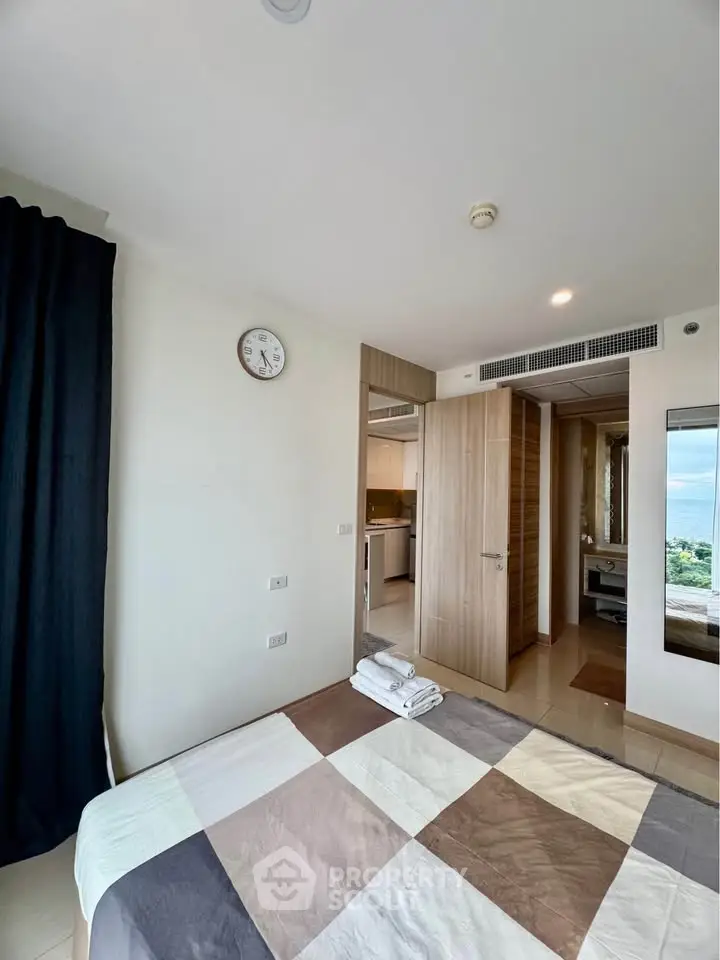 Modern bedroom with ocean view, featuring stylish decor and open layout leading to kitchen.