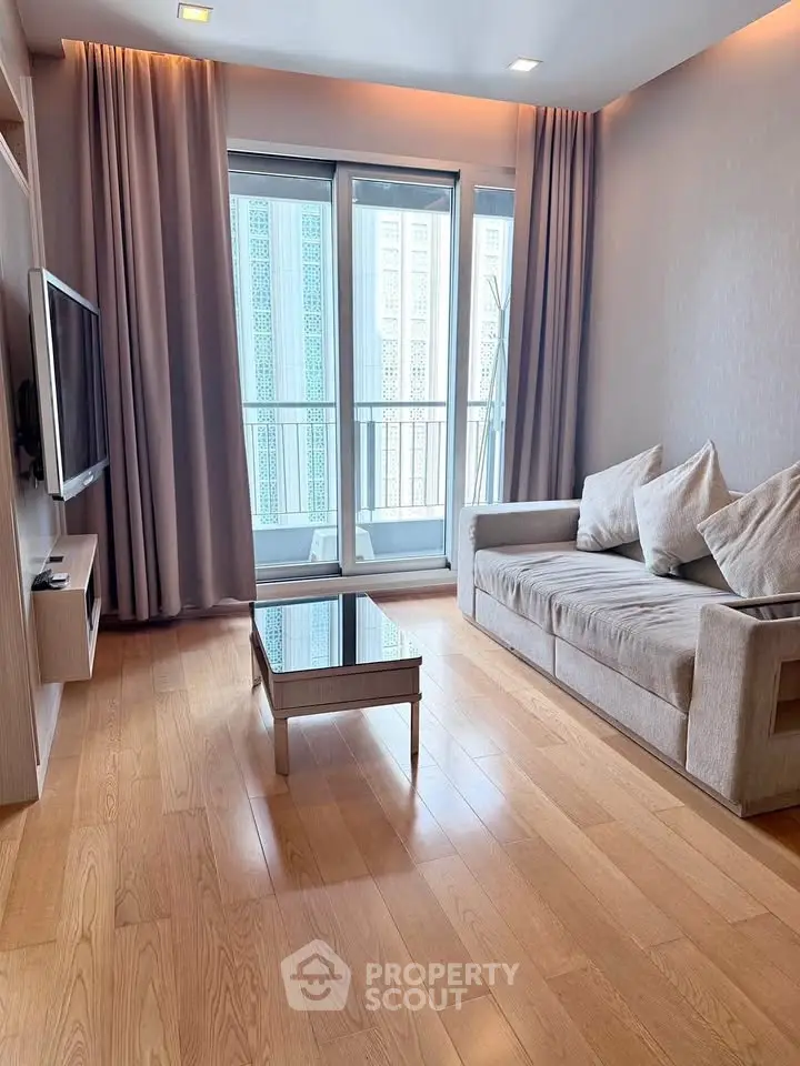 Modern living room with wooden flooring, cozy sofa, and large windows for natural light.