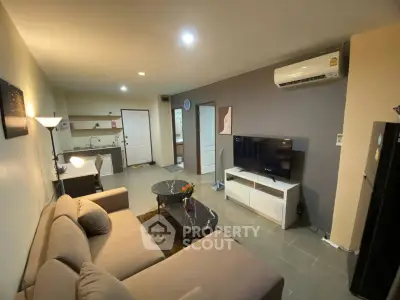 Modern living room with cozy sofa, TV, and open kitchen layout in stylish apartment.