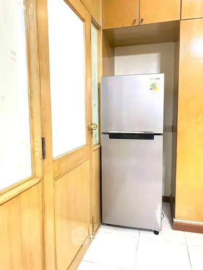 Modern kitchen corner with sleek stainless steel fridge and wooden cabinetry.