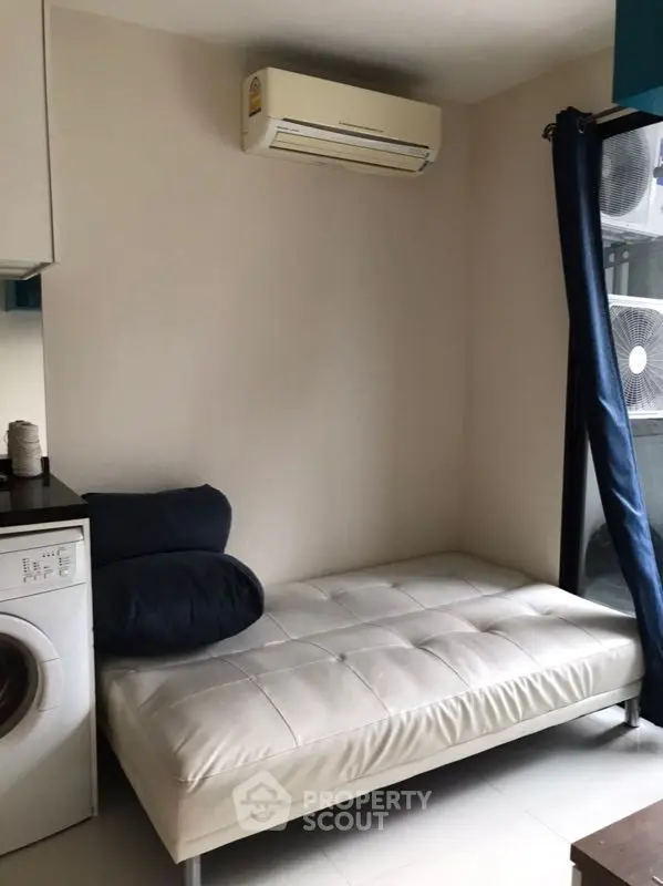 Cozy living room with modern sofa and air conditioning, featuring a washing machine for convenience.