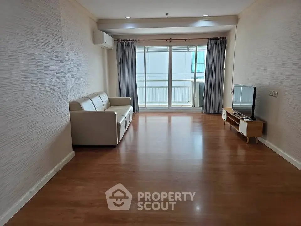 Spacious living room with wooden flooring and large window in modern apartment