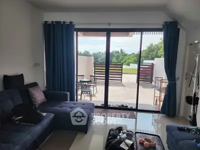 Spacious living room with large glass doors opening to a patio with outdoor seating.
