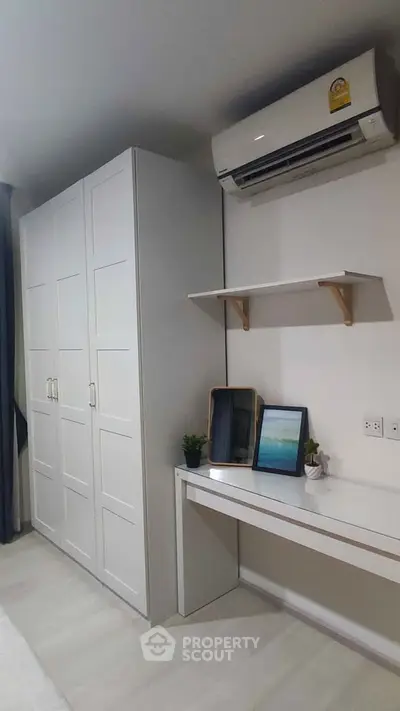 Modern bedroom with sleek white wardrobe and air conditioning unit