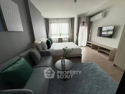 Modern bedroom with cozy seating area and large window, featuring stylish decor and natural light.