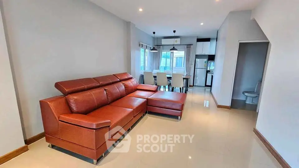 Spacious living room with modern leather sofa and dining area in open layout