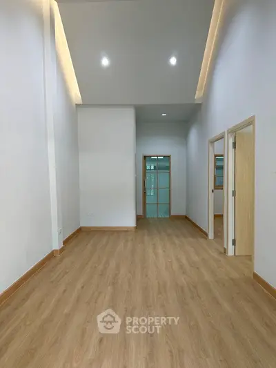 Spacious modern interior with wooden flooring and high ceiling, perfect for versatile living space.