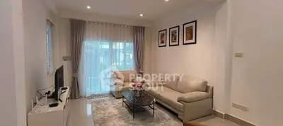 Elegant living room with modern decor, cozy seating, and natural light through large windows.