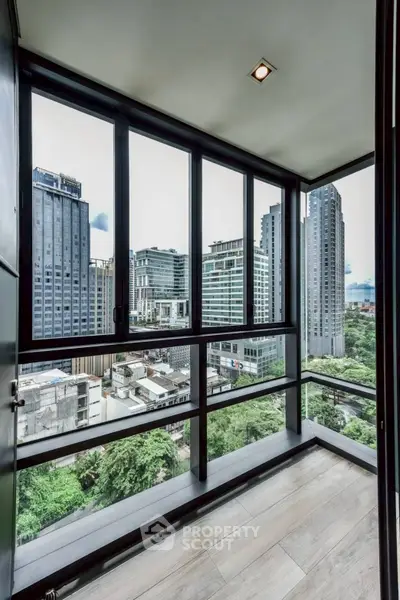 Stunning city view from a modern high-rise balcony with floor-to-ceiling windows.