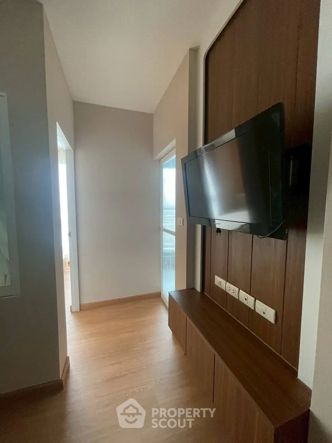 Modern hallway with mounted TV and wooden flooring in a stylish apartment.