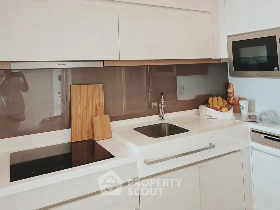 Modern kitchen with sleek white cabinetry, built-in appliances, and stylish backsplash.