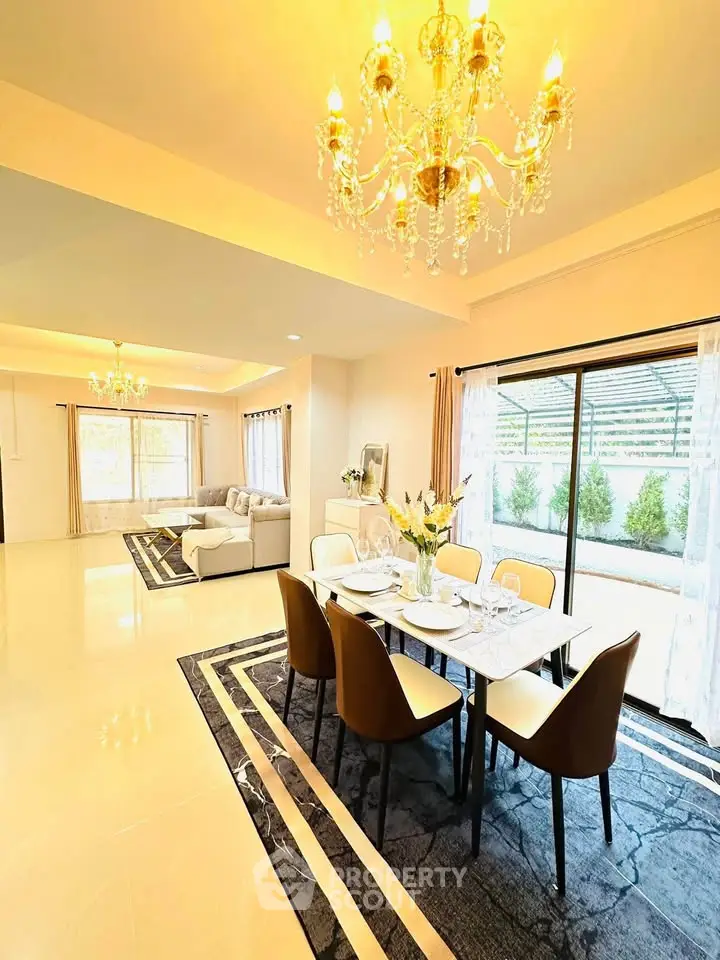 Luxurious open-plan living and dining area with elegant chandeliers and garden view.